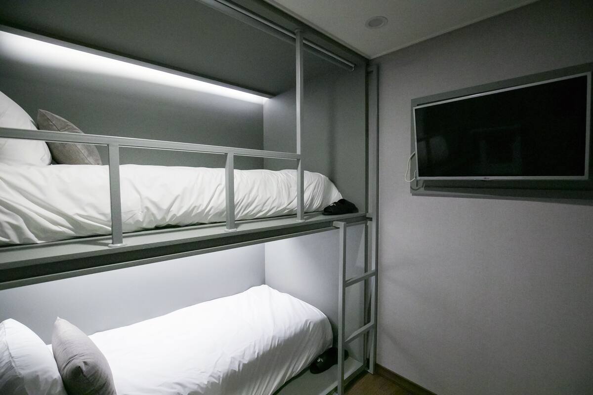 Habitación con literas y un televisor en la pared.