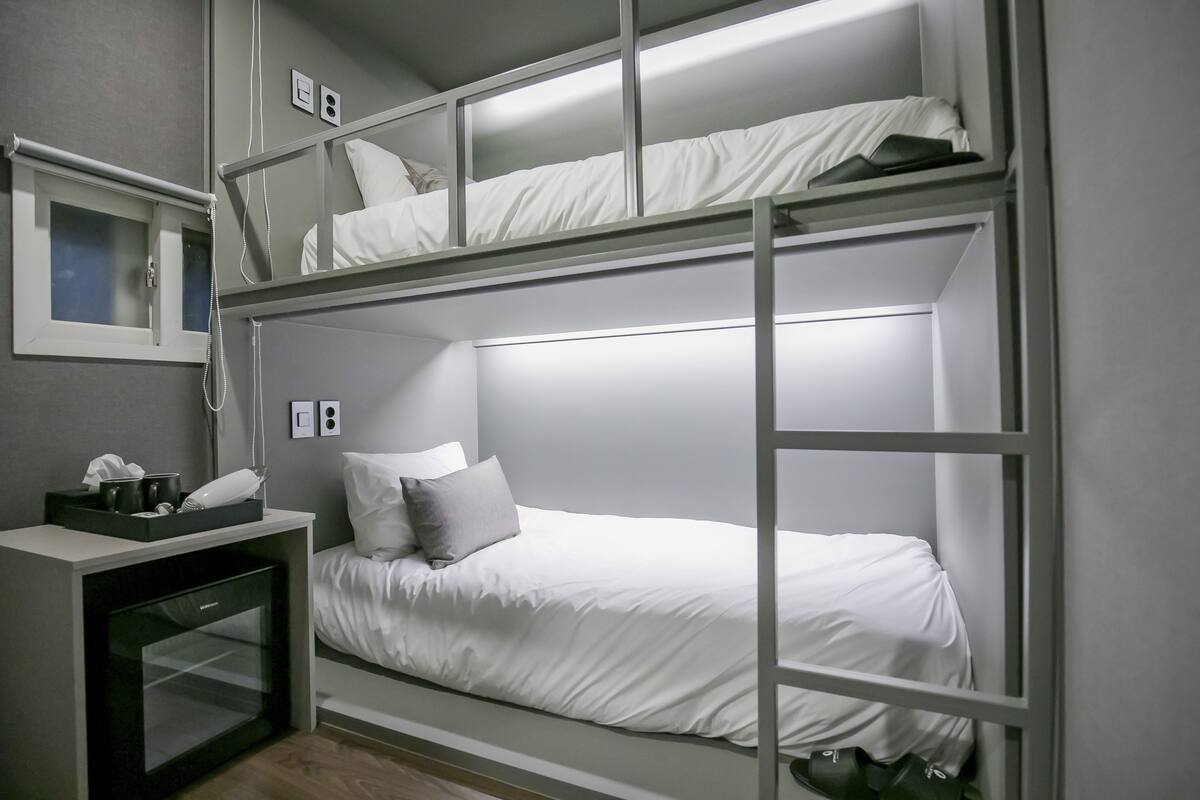 Habitación con literas, un escritorio y una ventana pequeña.