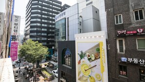 Una concurrida calle urbana con edificios modernos, incluyendo un restaurante con un gran letrero amarillo.