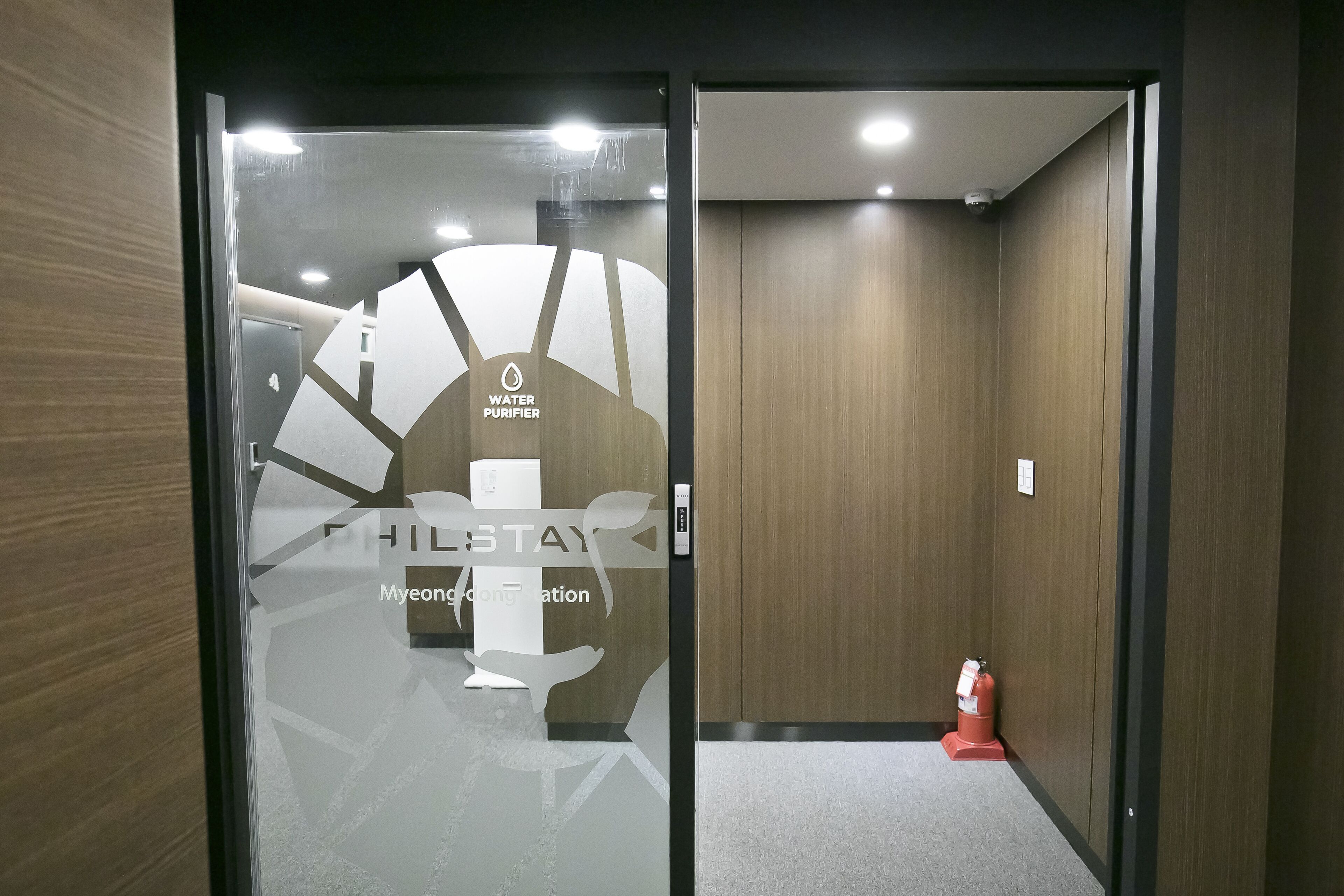 A hotel entrance with a glass door, a water purifier sign, and a fire extinguisher.