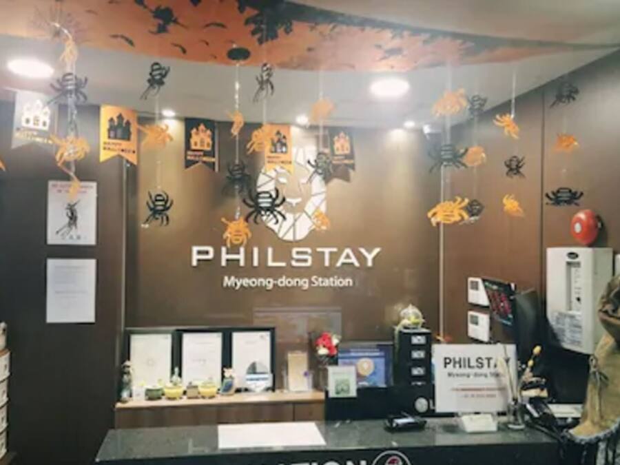 A PHILSTAY station with a reception desk, framed certificates, and spider decorations.