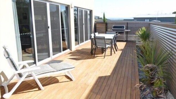 Una terrazza con tavolo e sedie, una poltrona relax e una pianta in vaso.