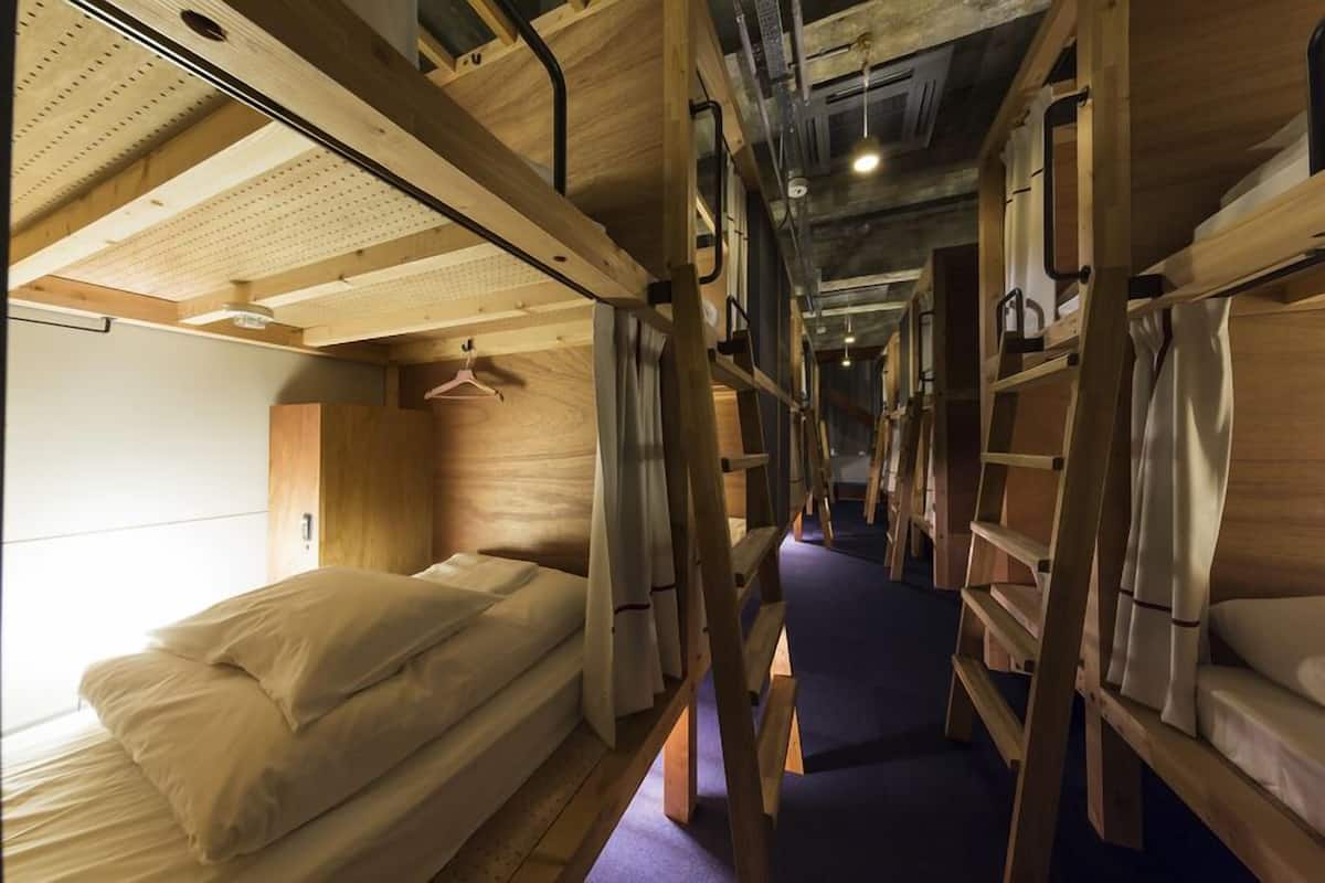 Ein schmaler Korridor mit Etagenbetten an beiden Seiten, Holzwänden und einer Hängestange.