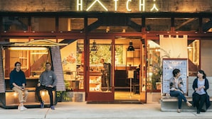 Une devanture de magasin avec une enseigne au néon indiquant le mot « HATCH ».