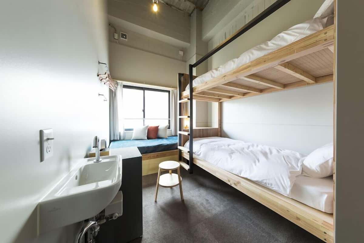 A bunk bed room with a sink and a window.