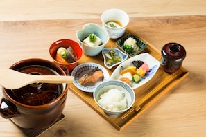 Una bandeja de madera con diversos platos japoneses, incluyendo arroz, pescado y verduras.