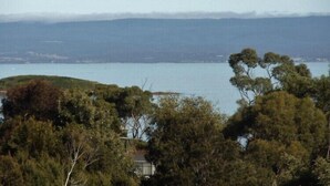 A coastal landscape with a body of water, hills, and dense vegetation. - Coles Bay House (Coles Bay)