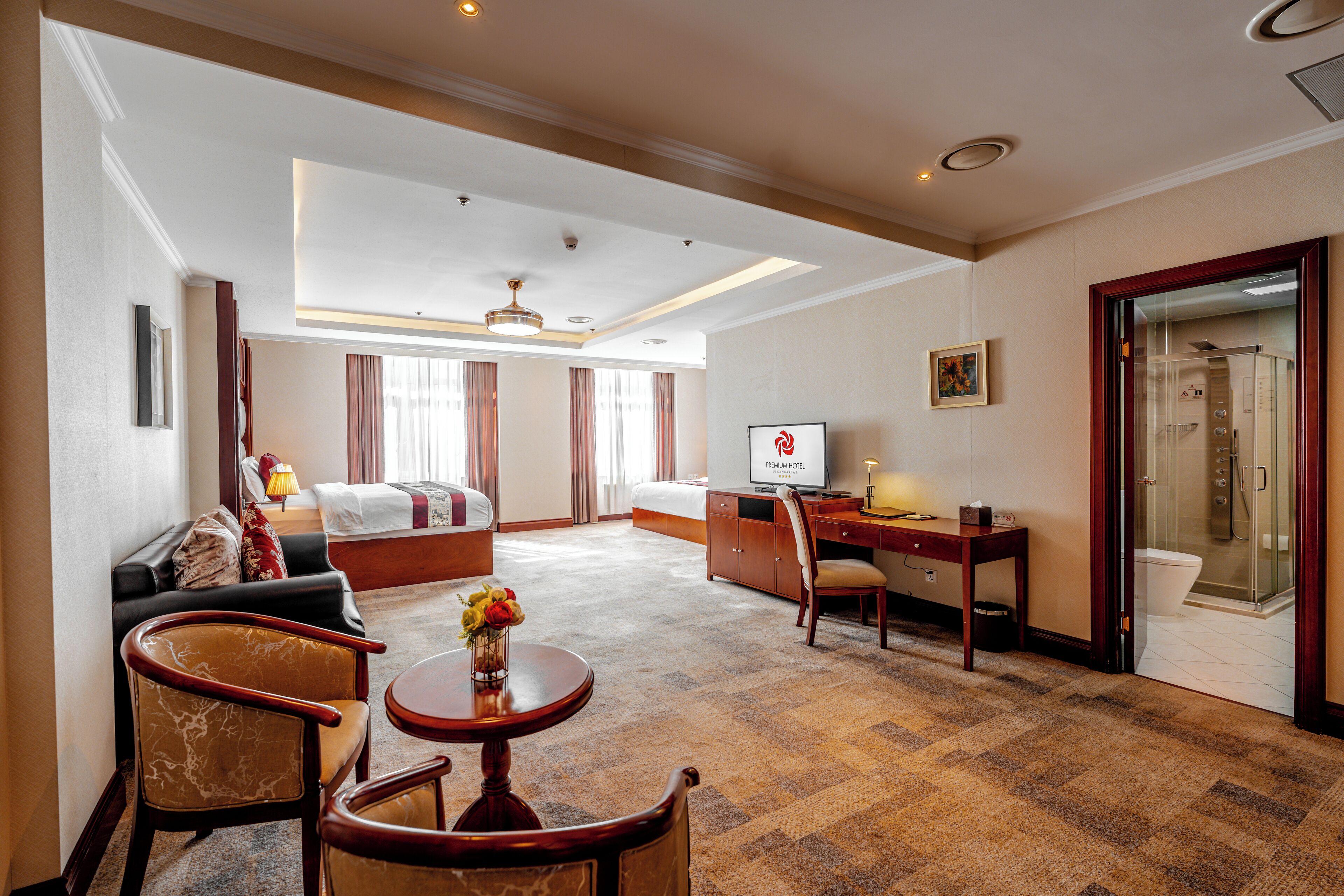 A hotel room with a living area, a bedroom, a desk, and a shower.