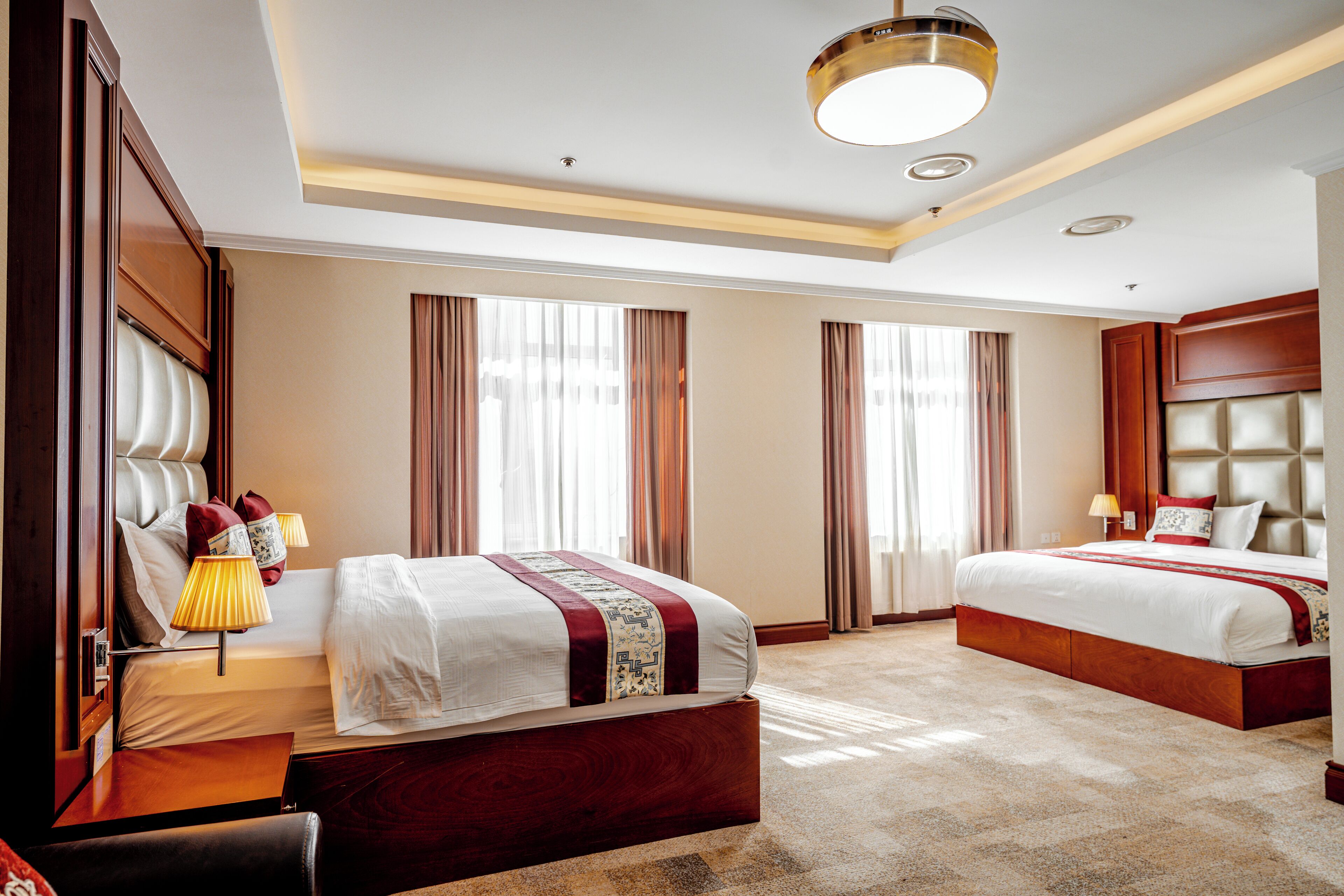 A hotel room with a large bed, a smaller bed, a desk, and a chair.