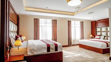 A hotel room with a large bed, a smaller bed, a desk, and a chair.
