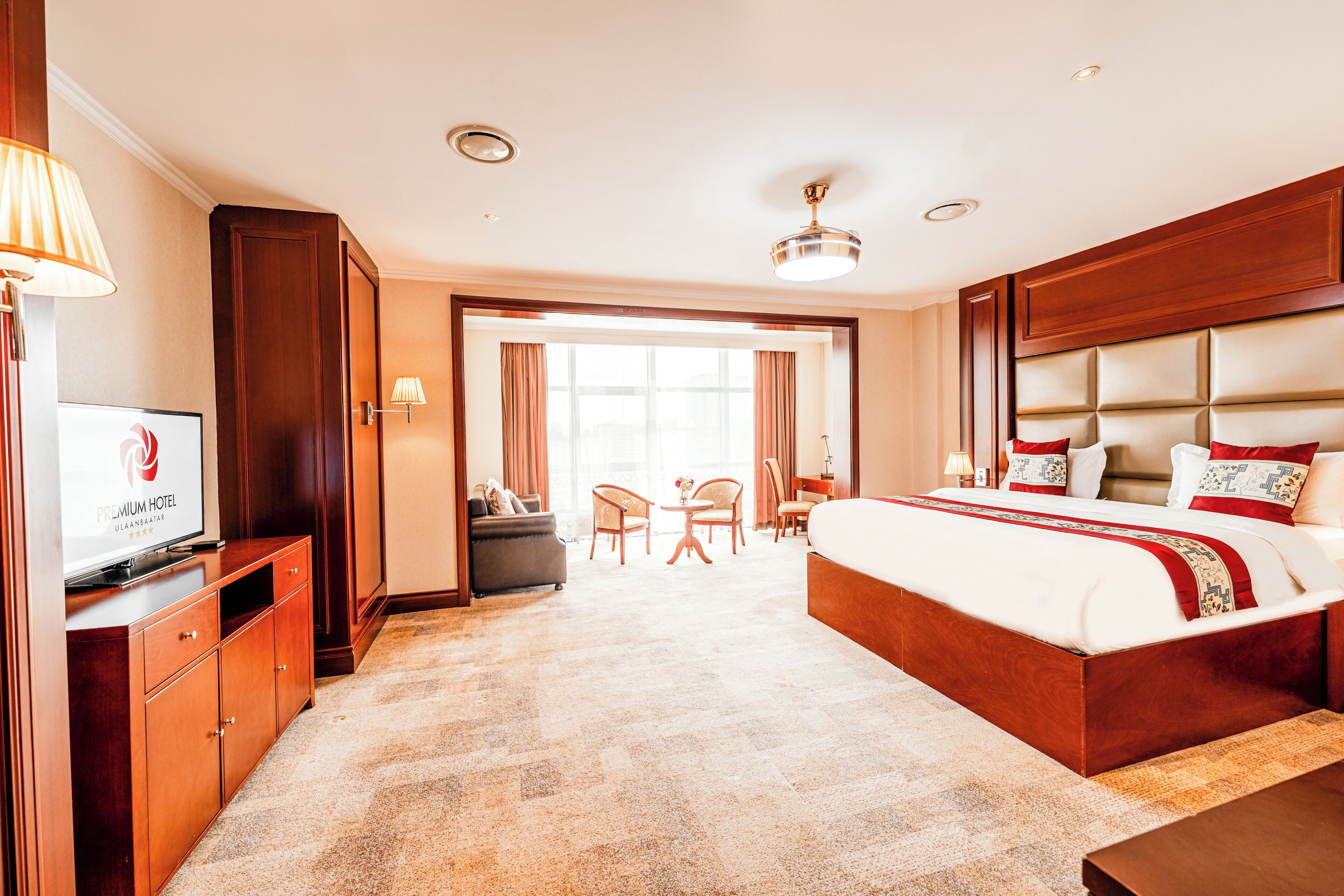 Ein Hotelzimmer mit einem großen Bett, einem Schreibtisch, einem Sessel, einem Fernseher und Blick auf die Stadt durch das Fenster.