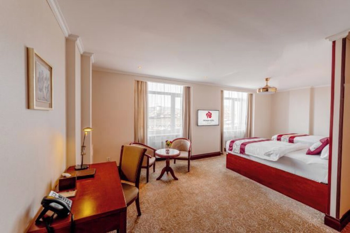 A hotel room with a bed, desk, chair, and a small table.