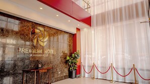 A hotel lobby with a large chandelier, a reception desk, and a decorative floor pattern.