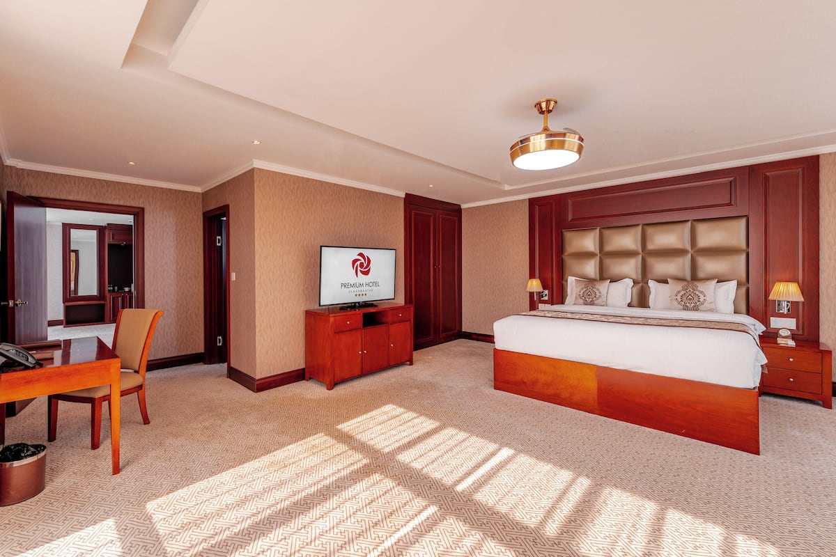 A hotel room with a large bed, a desk, a television, and a headboard with a tufted design.