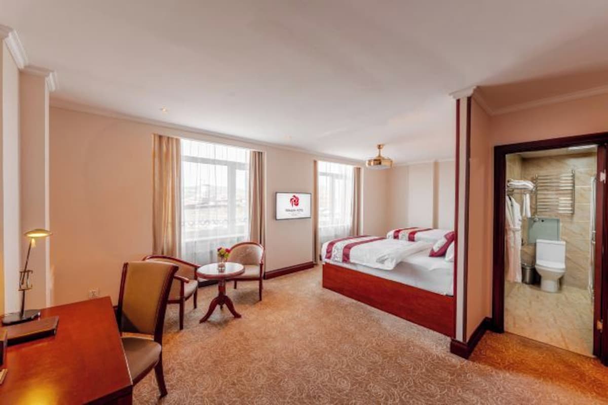 Una habitación de hotel con cama, escritorio, silla y una mesita.
