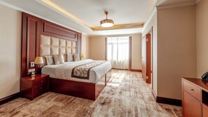 A hotel room with a large bed, a nightstand, a desk, and a ceiling light. - Premium Hotel Ulaanbaatar (Ulaanbaatar)