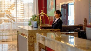 A reception desk with a marble top, a fire alarm control panel, and a large window with curtains. - Premium Hotel Ulaanbaatar (Ulaanbaatar)