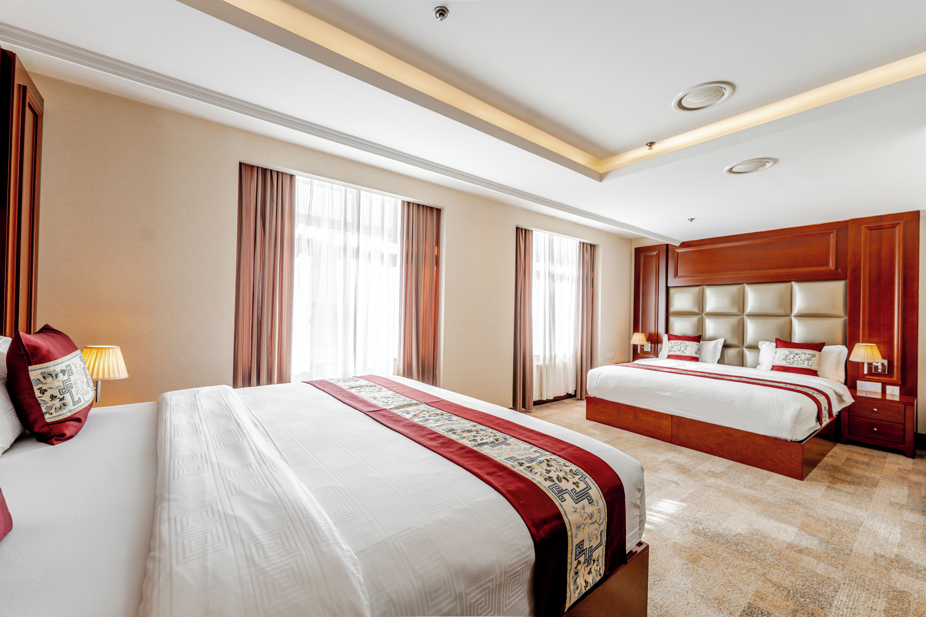 Habitación de hotel con dos camas, un ventanal grande y cabecero de madera.