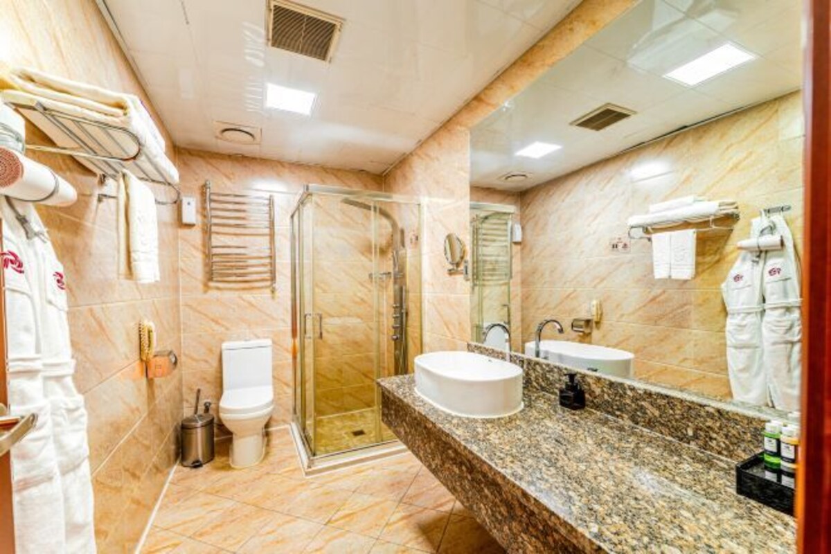 A modern bathroom with a glass-enclosed shower, a white sink, and a large mirror.