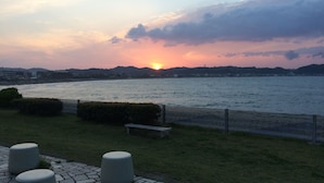 A riverside view with a sunset, stone seating, and a fence. - Guest House Kamakura Zen-ji - Hostel (Kamakura)
