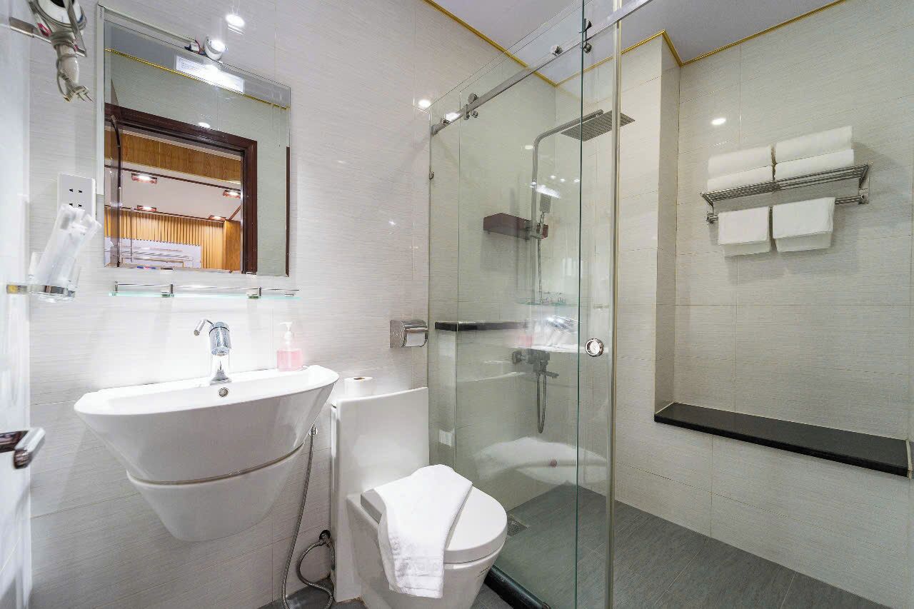 A modern bathroom with a glass-enclosed shower, a white sink, and a toilet.