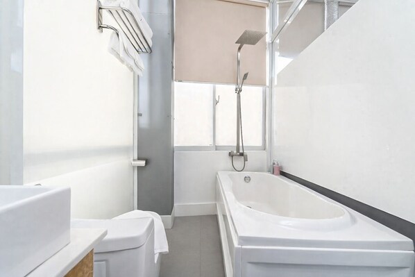 Un baño moderno con bañera, ducha e inodoro.