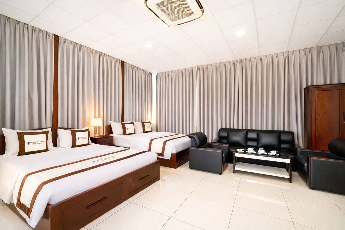 A hotel room with two beds, a sofa, a coffee table, and a wardrobe.