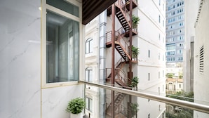 A modern apartment with a marble wall, a large window, a balcony with a glass railing, and a fire escape. - Diamond Luxury Ben Thanh (Ho Chi Minh City)