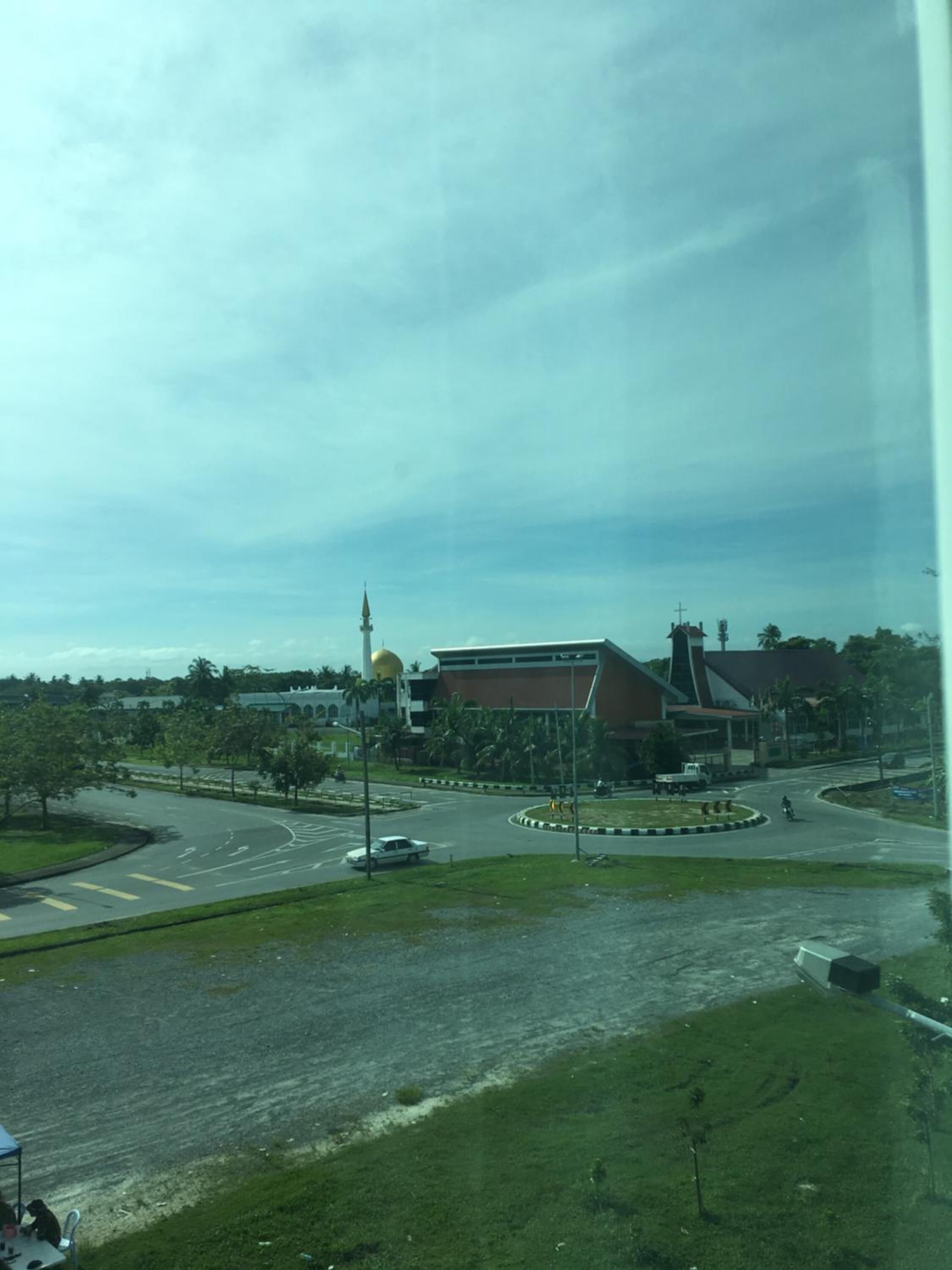 A view of a roundabout with a church and a modern building in the background.