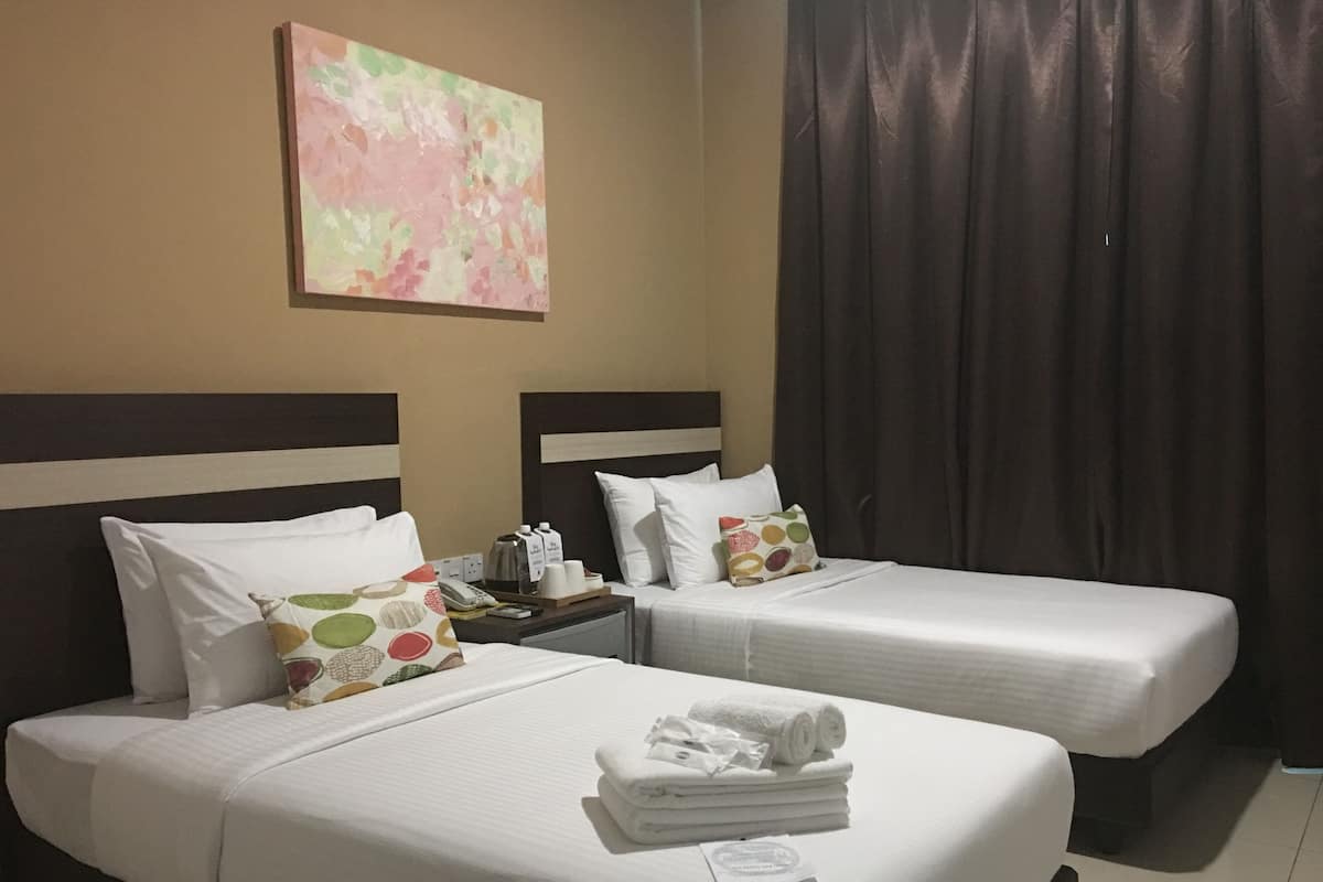 Une chambre d’hôtel avec deux lits, une table de chevet et un tableau au mur.