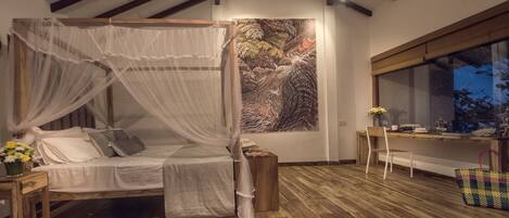 A bedroom with a canopy bed, a large painting, a desk, and a window.