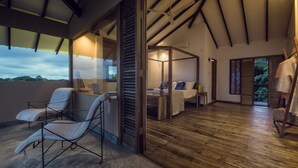 Habitación amplia con una cama grande, un escritorio con una computadora portátil y una silla. Tiene un balcón con una silla y una mesa.