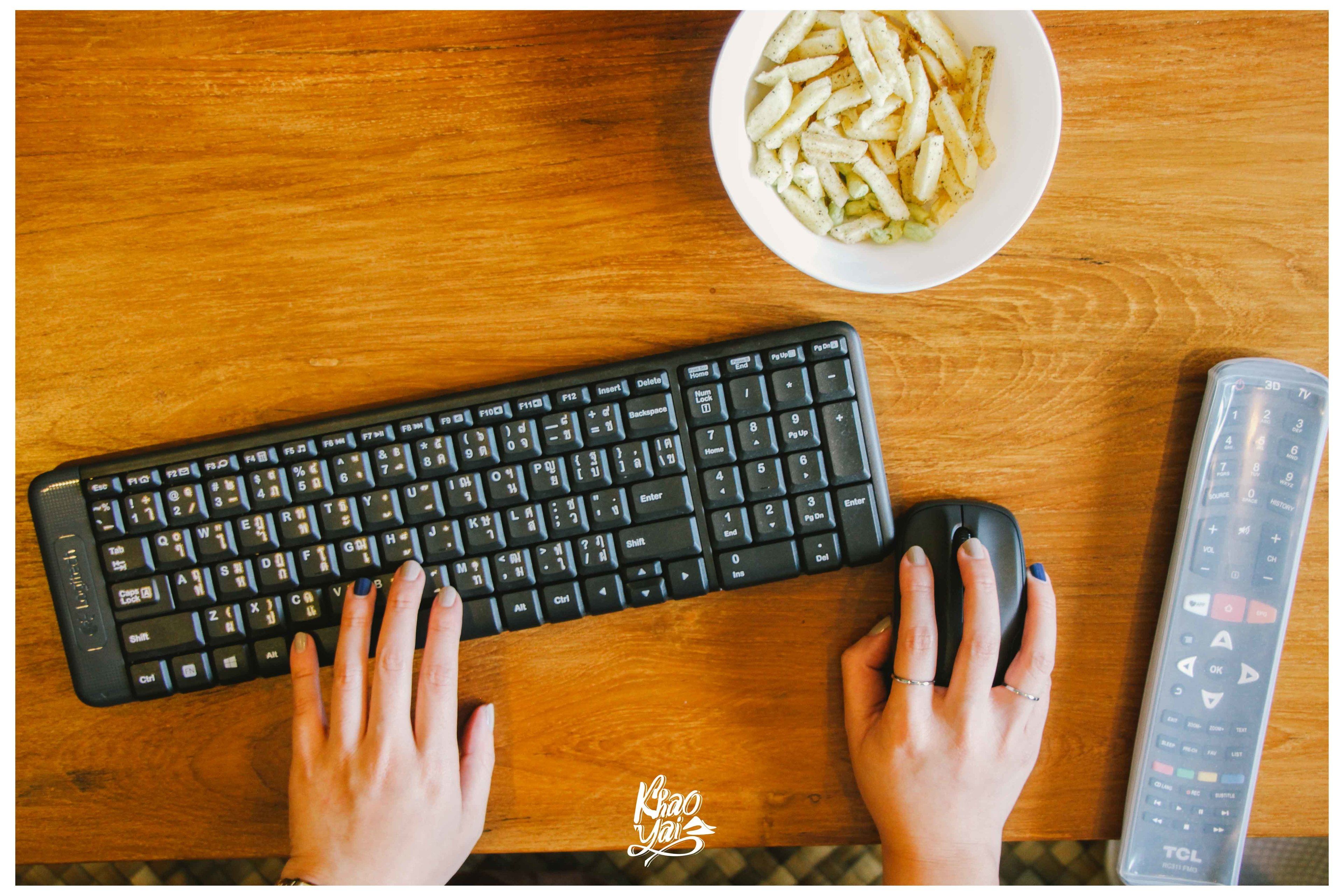 Un teclado, un control remoto y un cuenco de papas fritas sobre una mesa de madera.