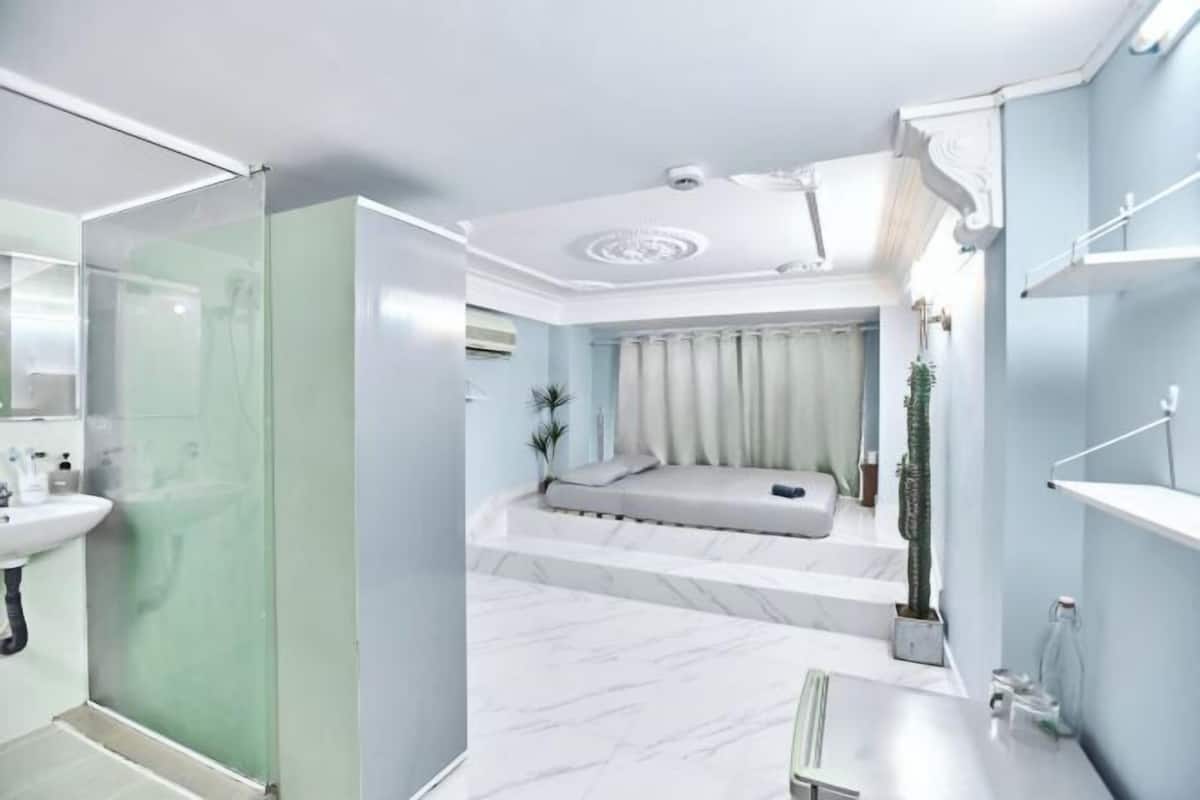 A modern bathroom with a glass shower enclosure, a marble sink, and a built-in bench with a plant.