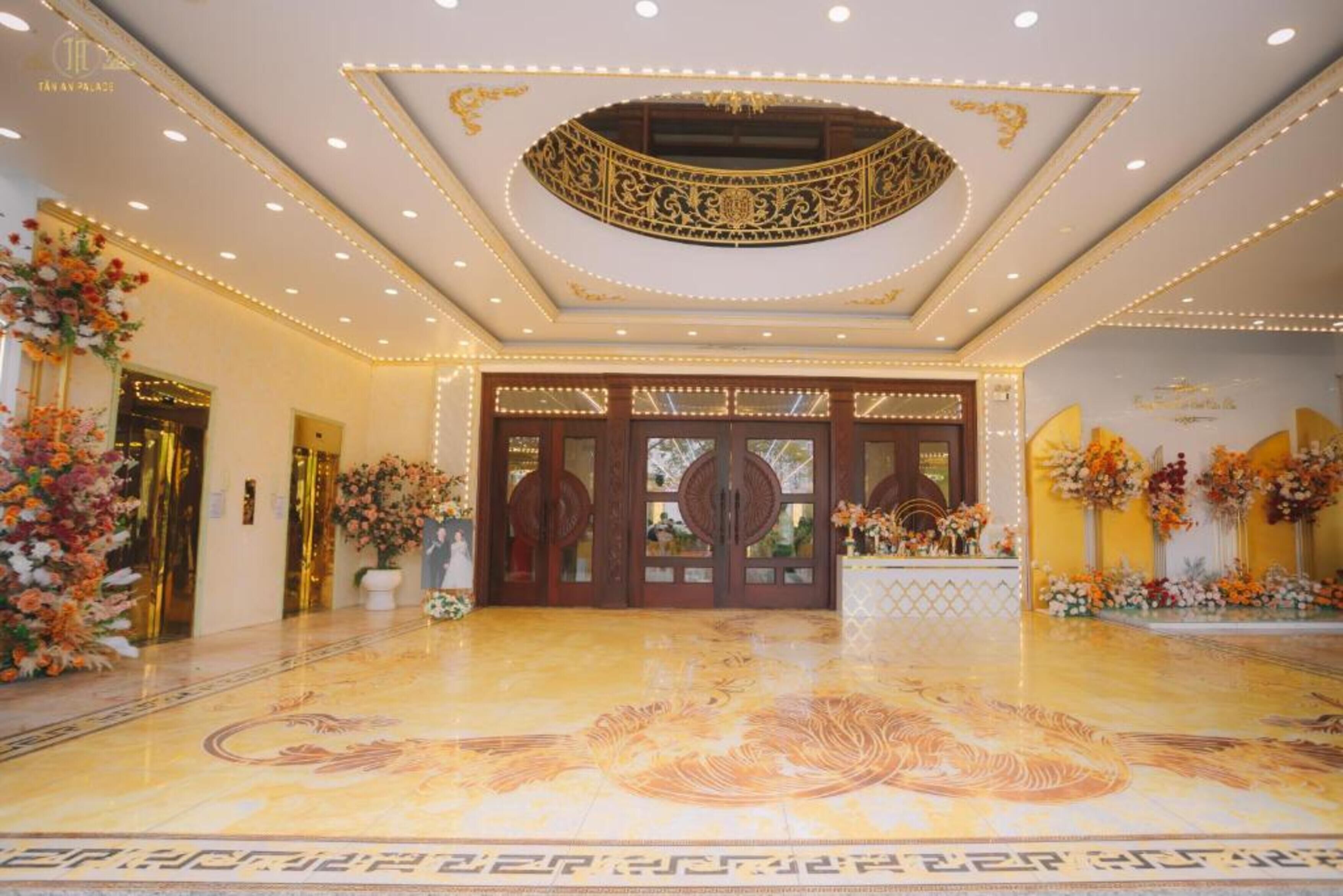 Um hall imponente com detalhado design no teto, piso de mármore e decoração floral.