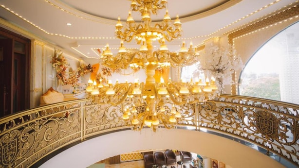 A grand chandelier in a luxurious room with ornate railings and a view of the city. - Tan An Palace (Hai Phong)