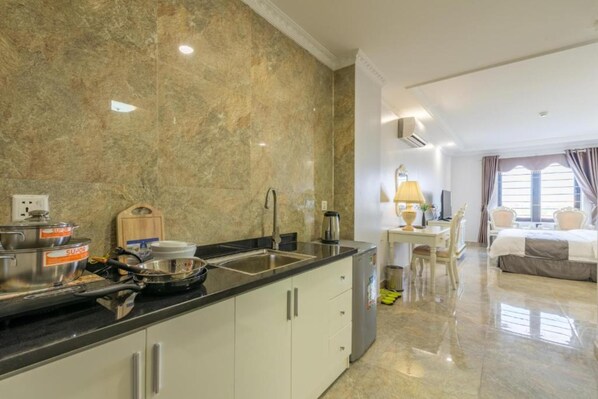 A modern kitchen with granite countertops, a sink, and a dining area with a table and chairs. - Tan An Palace (Hai Phong)