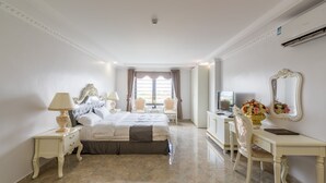 A spacious bedroom with a large bed, two bedside tables with lamps, a vanity with a mirror, and a desk with a chair. - Tan An Palace (Hai Phong)