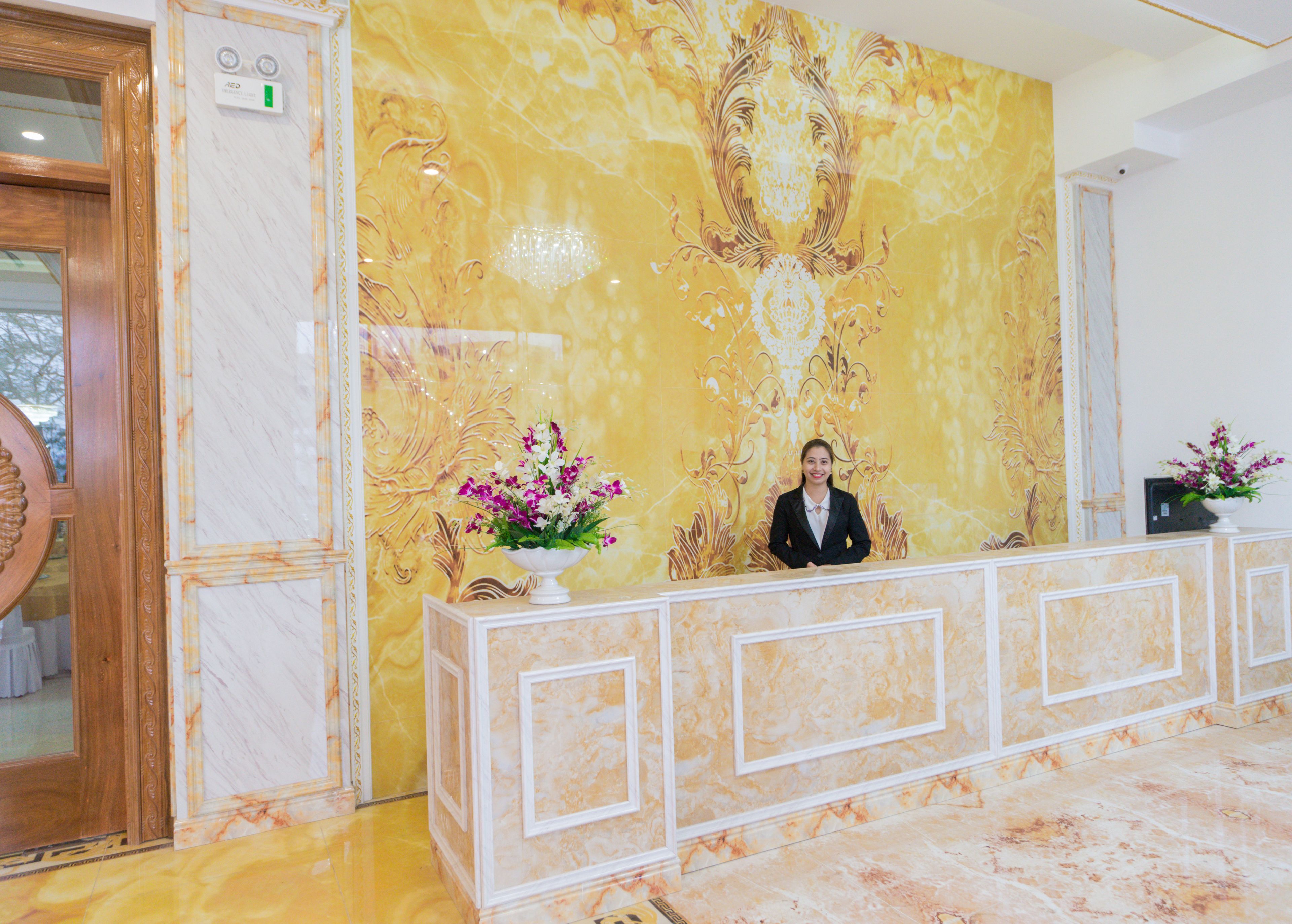 Un mostrador de recepción con pared de mármol y un arreglo floral.