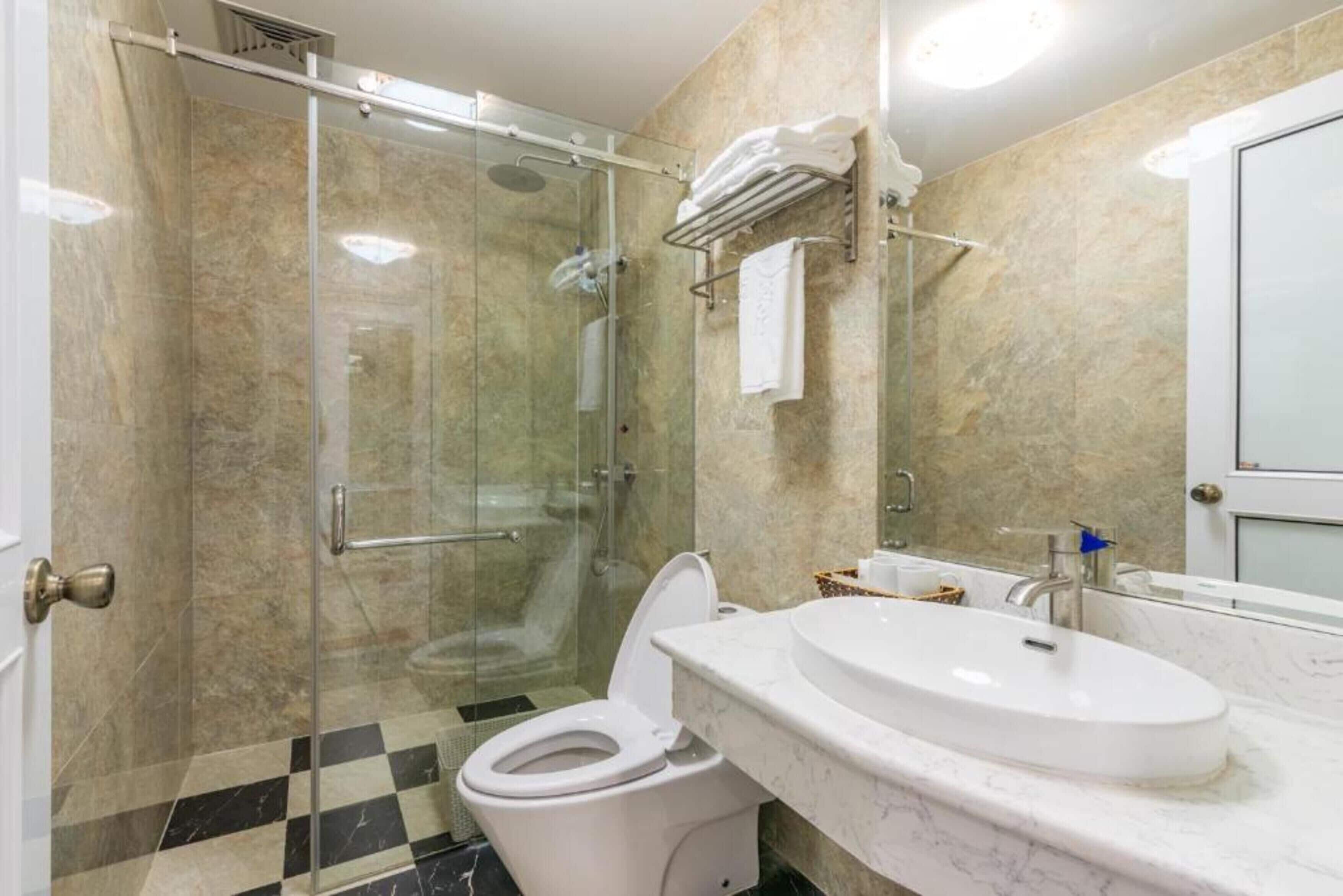 Un baño moderno con ducha de vidrio, inodoro blanco y lavamanos de mármol.