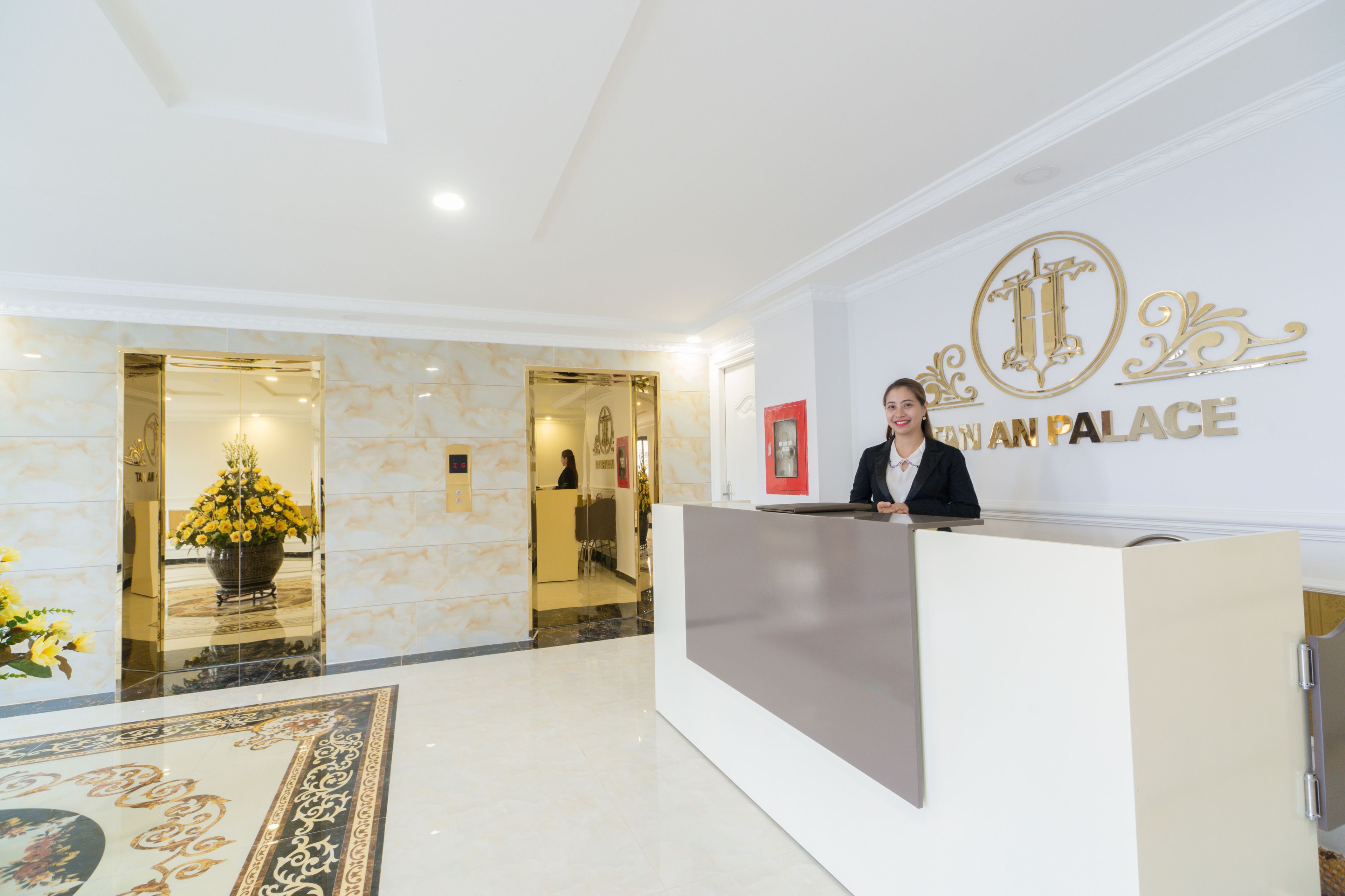Zona de recepción con piso de mármol, mostrador de recepción y pared con logotipo y nombre.