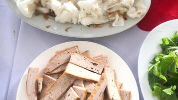 A table with a plate of sliced meat, a plate of white food, and a bowl of soup.