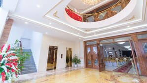 A grand lobby with marble flooring, a staircase, and a balcony with ornate railings. - Tan An Palace (Hai Phong)