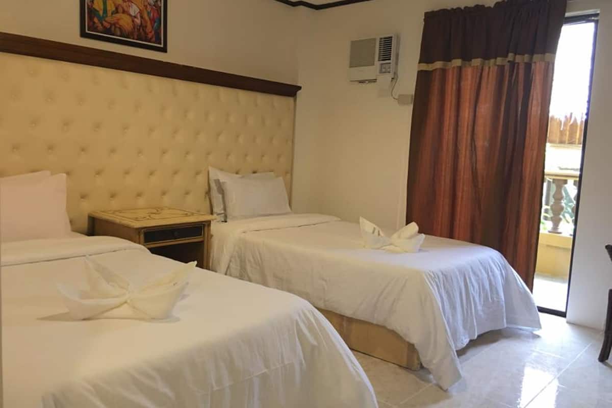 A hotel room with two beds, a large window with curtains, an air conditioning unit, and a painting on the wall.