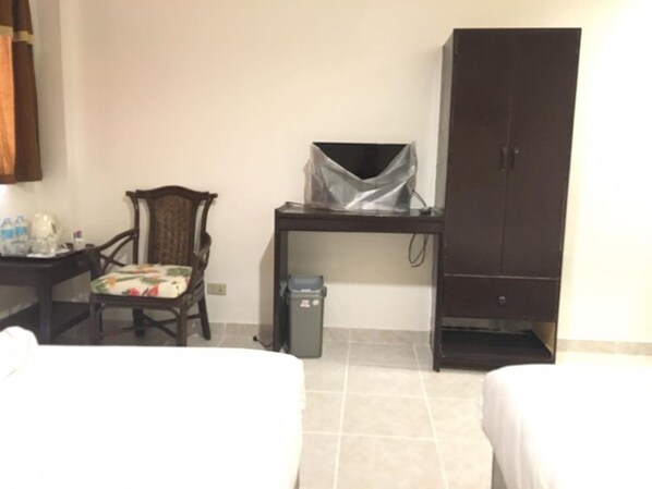 Una habitación de hotel con una cama, un escritorio con una computadora, una silla y un armario.