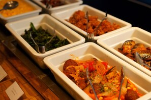 A buffet with various dishes including greens, meat, and vegetables.