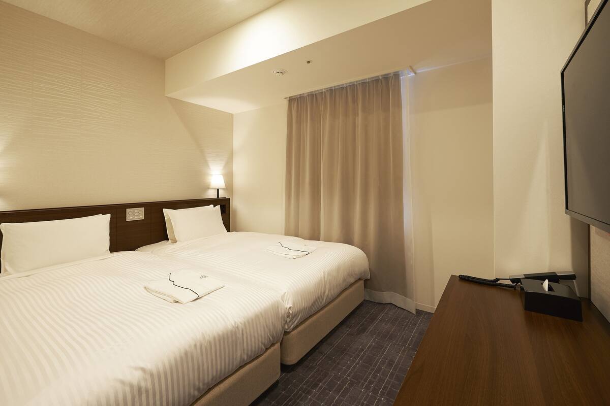A hotel room with a large bed, a flat-screen TV, and a bedside table.