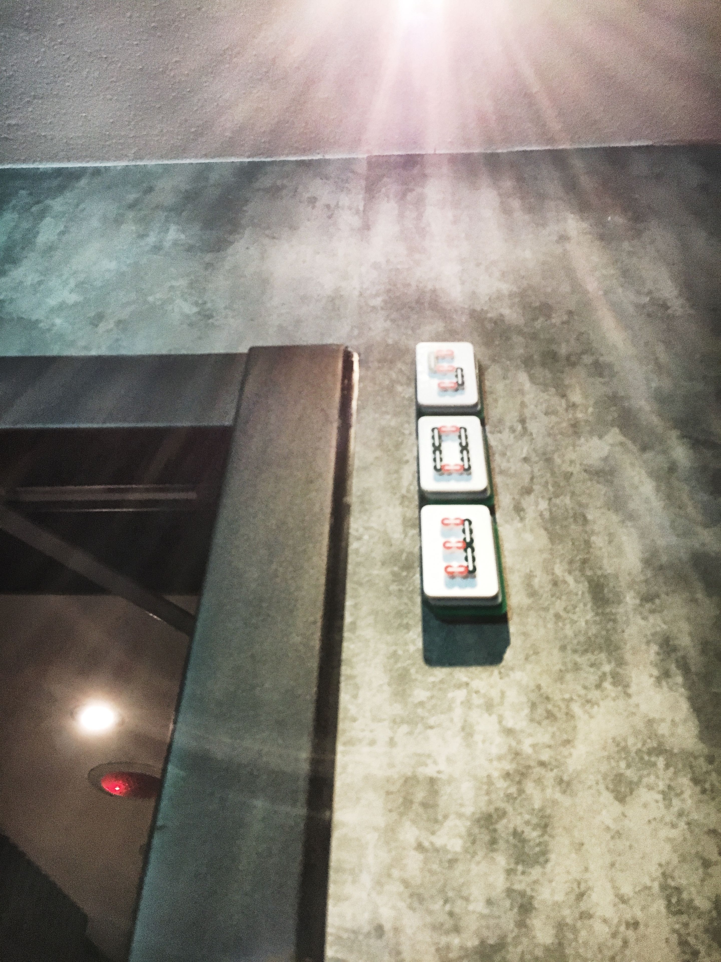 A parking area with four parking meters and a red light on the ground.