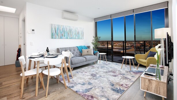 A modern living room with a dining area, large windows, and a city view. - StayCentral - Northcote Hill Penthouse (Northcote)