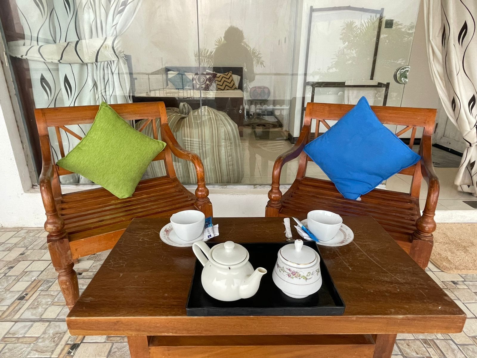 A wooden table with a tray holding a teapot, cups, and saucers.